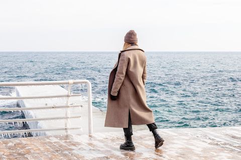 Mantel-Trend 2025: Frau steht am Wasser und trägt einen Wollmantel