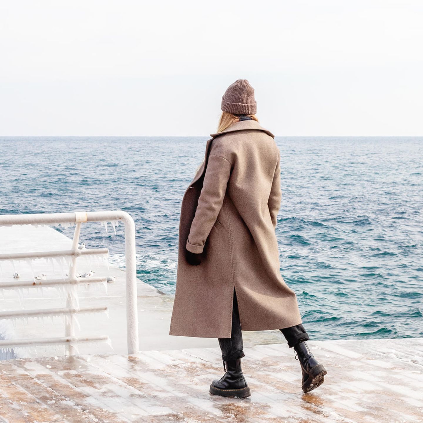 Mantel-Trend 2025: Frau steht am Wasser und trägt einen Wollmantel