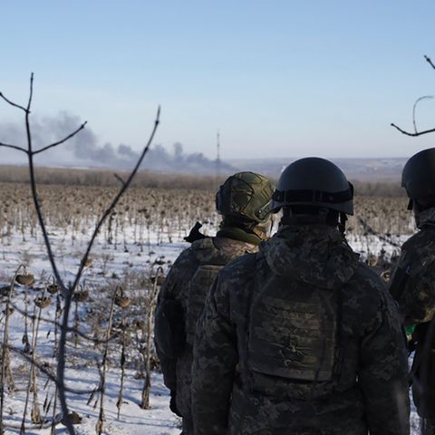 Ukrainische Soldaten blicken auf das brennende Soledar. Die Stadt ist komplett zerstört.