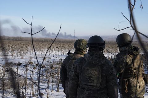 Ukrainische Soldaten blicken auf das brennende Soledar. Die Stadt ist komplett zerstört.