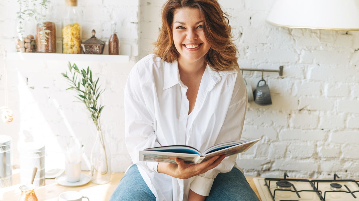 Kochbuch gesunde Ernährung Eine Frau sitzt in der Küche mit einem Kochbuch in der Hand