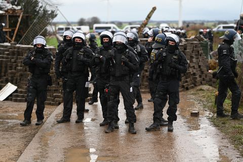 Polizisten rücken nach Lützerath vor, hinter ihnen eine aus Ziegelsteinen errichtete Barrikade