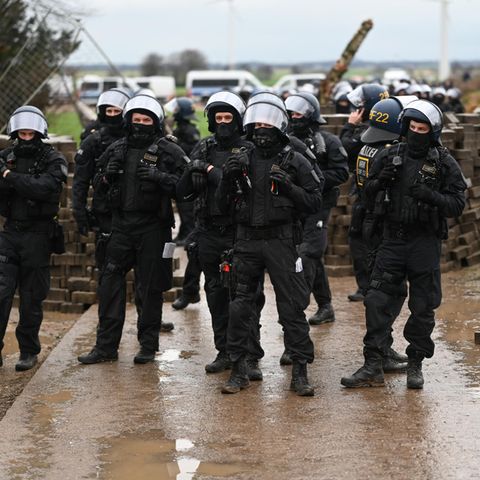 Polizisten rücken nach Lützerath vor, hinter ihnen eine aus Ziegelsteinen errichtete Barrikade
