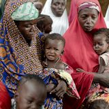 Eine Gruppe von Frauen hat sich mit ihren Kindern in der Nähe einses Bezirkskrankenhauses in der Sahelzone versammelt.  Niger gehört zu den ärmsten Ländern der Welt. Rund 40 Prozent der Bevölkerung des westafrikanischen Wüstenstaates leben unter der nationalen Armutsgrenze. Etwa 1,7 Millionen Menschen sind aktuell von Hunger betroffen. Fast die Hälfte aller Kinder unter fünf Jahren ist chronisch unterernährt. Auf dem aktuellen UN-Index der menschlichen Entwicklung belegt das Land Rang 189 von 191 gelisteten Staaten.  Nigers schnell wachsende Bevölkerung ist immer wieder mit längeren Dürreperioden und Nahrungskrisen konfrontiert. Verschärft wird die Situation seit einigen Jahren durch Angriffe der radikalislamischen Miliz Boko Haram, die beiderseits der Grenze zu Nigeria aktiv ist. Zehntausende Menschen sind zudem aus Angst vor Angriffen bewaffneter Gruppen aus den Nachbarstaaten nach Niger geflüchtet