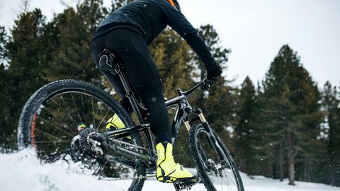 Fahrradbekleidung im Winter: Mountainbiker rast durch den Schnee