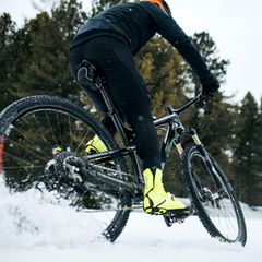 Fahrradbekleidung im Winter: Mountainbiker rast durch den Schnee