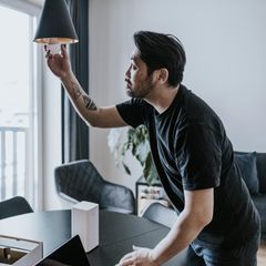 Energiesparen im Winter: Ein Mann schraubt eine Birne aus der Lampe.