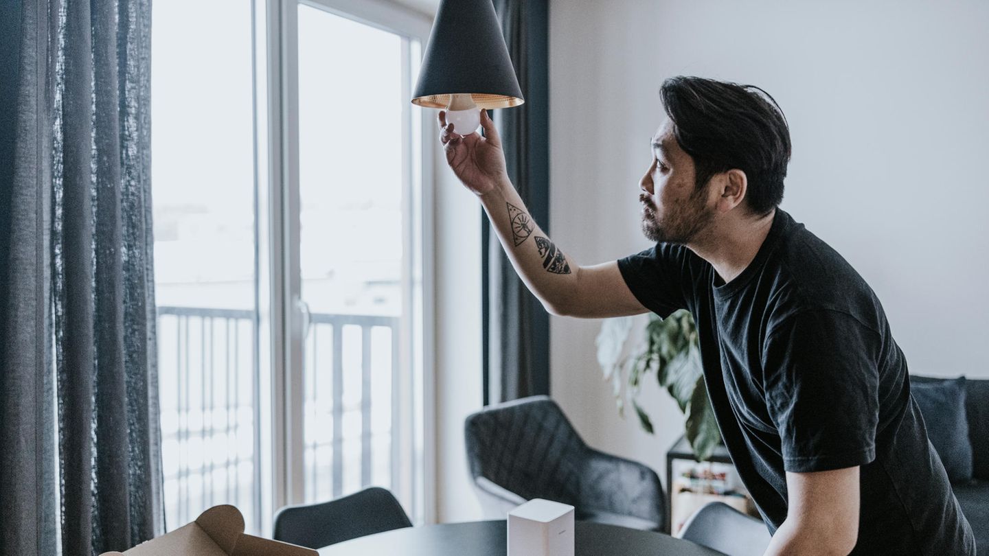 Energiesparen im Winter: Ein Mann schraubt eine Birne aus der Lampe.