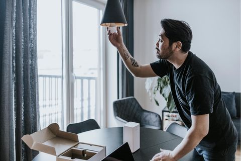 Energiesparen im Winter: Ein Mann schraubt eine Birne aus der Lampe.