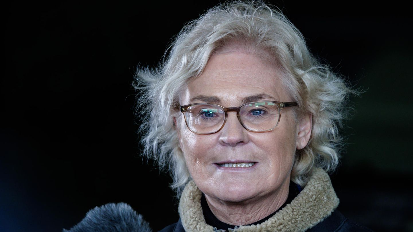 Christine Lambrecht, eine ältere weiße Frau mit graublonden Locken, spricht im Dunkeln in ein graues Mikrofon