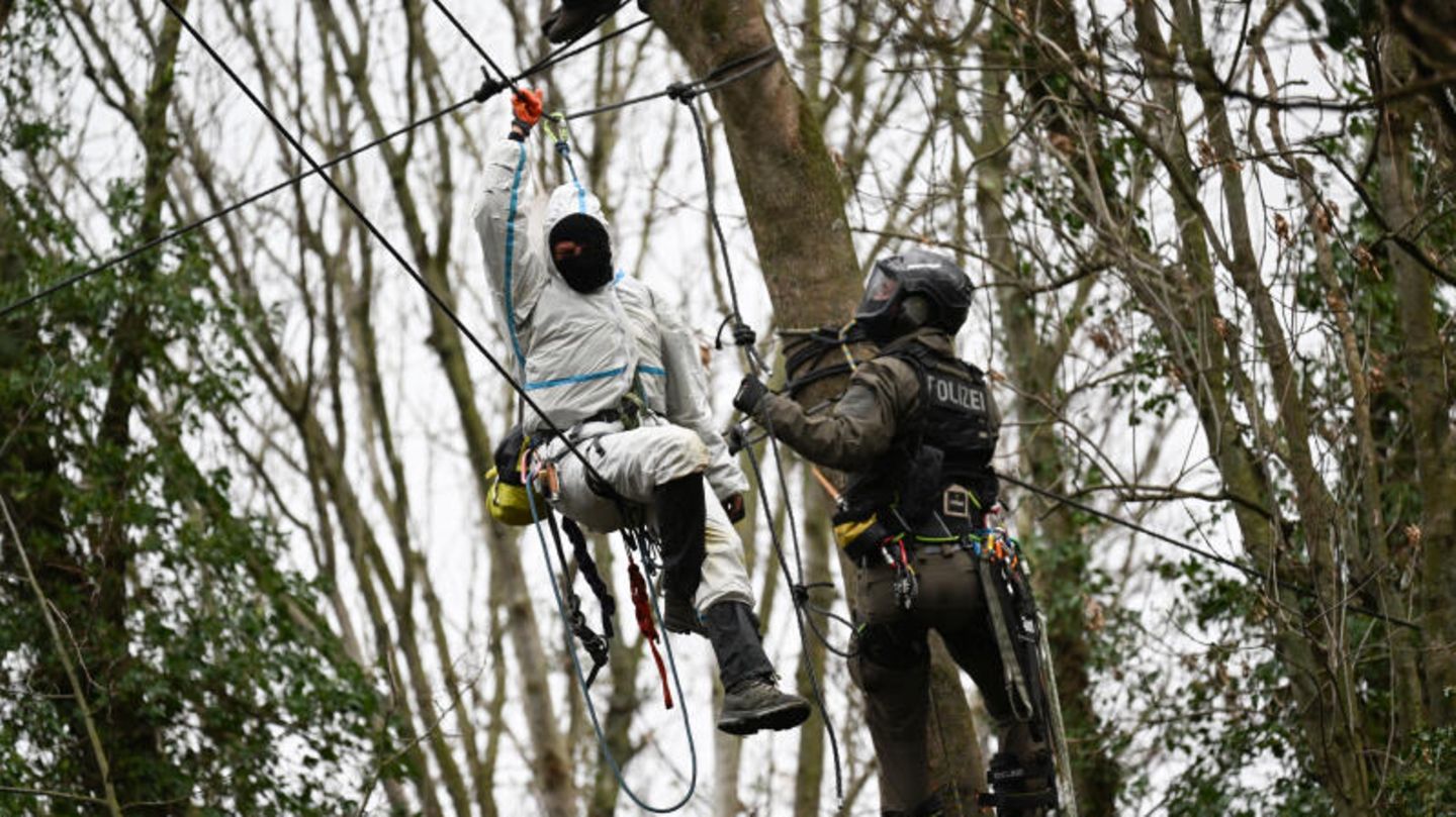 Ein Klimaktivist und ein Polizeikletterer hängen sich an einem Baum in Lützerath gegenüber Ein Klimaktivist und ein Polizeikletterer hängen sich an einem Baum in Lützerath gegenüber