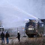 Die Polizei fährt mit einem Wasserwerfer bei einer Demonstration an Klimaaktivisten vorbei