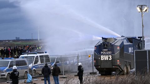 Die Polizei fährt mit einem Wasserwerfer bei einer Demonstration an Klimaaktivisten vorbei