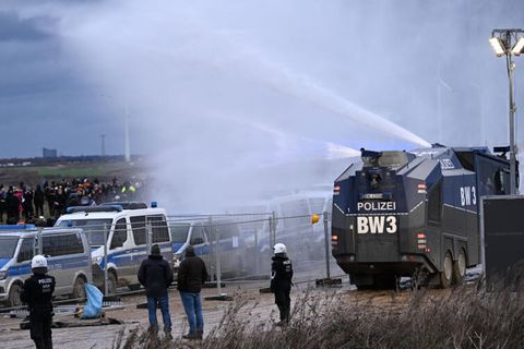 Die Polizei fährt mit einem Wasserwerfer bei einer Demonstration an Klimaaktivisten vorbei