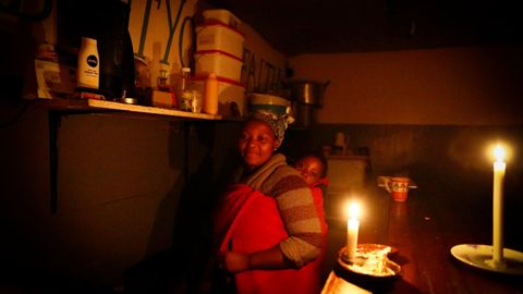  Eine Gastronomin aus Kapstadt muss ihr Imbissrestaurant bei Kerzenlicht betreiben. Es herrscht ein planmäßiger Stromausfalls, der als load shedding bekannt ist.