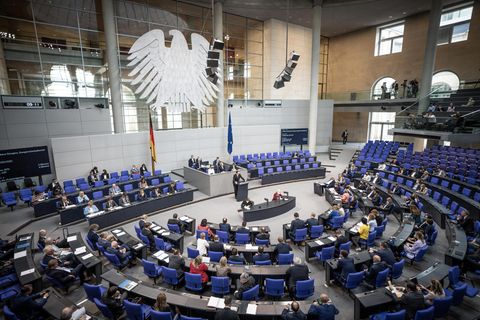 Von der Empore des Bundestags in Berlin schaut man ins Plenum, in dem die Abgeordneten unter einem silbernen Bundesadler sitzen