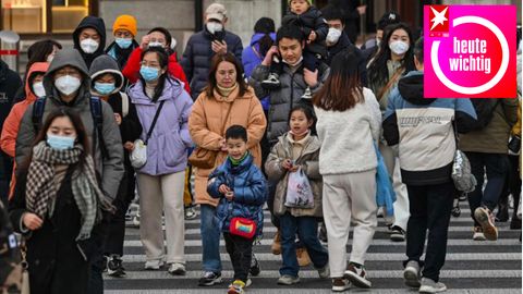 Menschen gehen mit und ohne Maske über eine belebte Einkaufsstraße in Shanghai, China