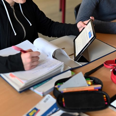 In einer Schulstunde sitzen drei Schülerinnen mit Tablets gemeinsam an einem Tisch