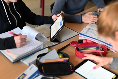 In einer Schulstunde sitzen drei Schülerinnen mit Tablets gemeinsam an einem Tisch