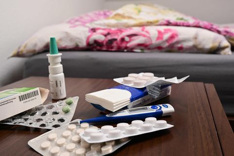 Auf einem Nachttisch liegen Medikamente, Nasenspray und Taschentücher