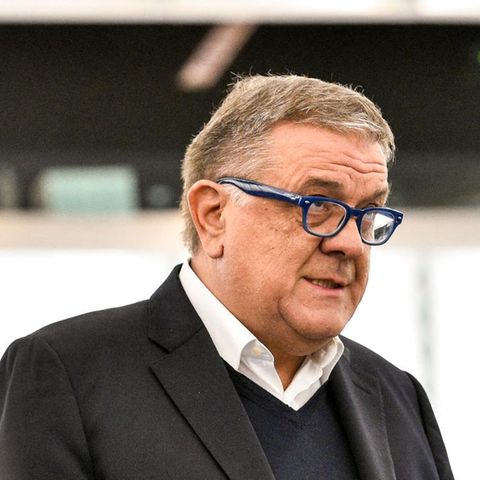 Pier Antonio Panzeri, ein älterer weißer Mann mit blauer Brille steht im Jackett vor einem Mikro und hält Zettel in der Hand