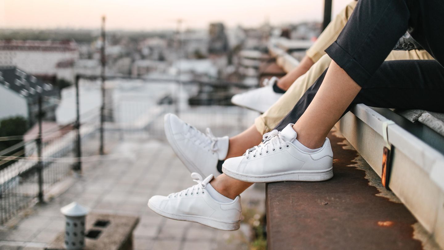 Personen sitzen mit weissen Sneaker auf dem Dach Personen sitzen mit weissen Sneaker auf dem Dach