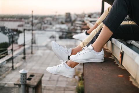 Personen sitzen mit weissen Sneaker auf dem Dach
