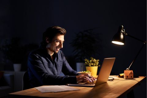 Ein Mann sitzt vor einem Laptop. Er arbeitet vermutlich Online.