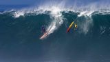 Oahu, Hawaii. Surfer Eli Olsen reitet eine Welle, während sein hawaiianischer Kollege Jake Maki in der Waimea Bay an der Nordküste von Big Island abgeworfen wird.