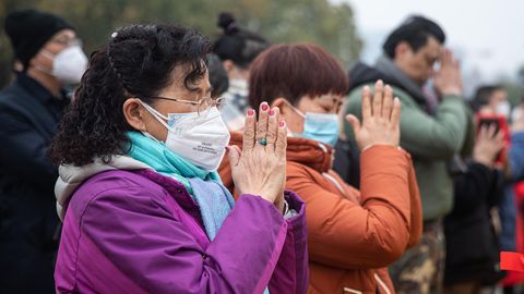 In Wuhan beten zwei Frauen, während sie OP-Masken gegen das Coronavirus tragen