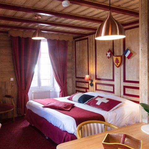 Hotelzimmer und Bett mit Kissen der Landesflaggen der Schweiz und Frankreichs
