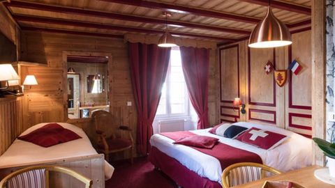 Hotelzimmer und Bett mit Kissen der Landesflaggen der Schweiz und Frankreichs