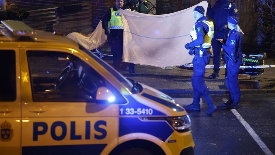 In Solna bei Stockholm verdecken Polizisten mit einem Tuch einen Tatort, an dem ein Toter liegt
