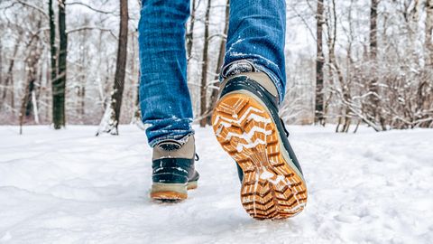 Deals und Angebote: ein Paar Männerbeine mit Jeans und Trekkingschuhen im Schnee