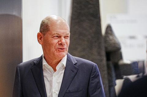 Olaf Scholz, ein älterer weißer Mann mit Halbglatze geht im Anzug durch eine Tür