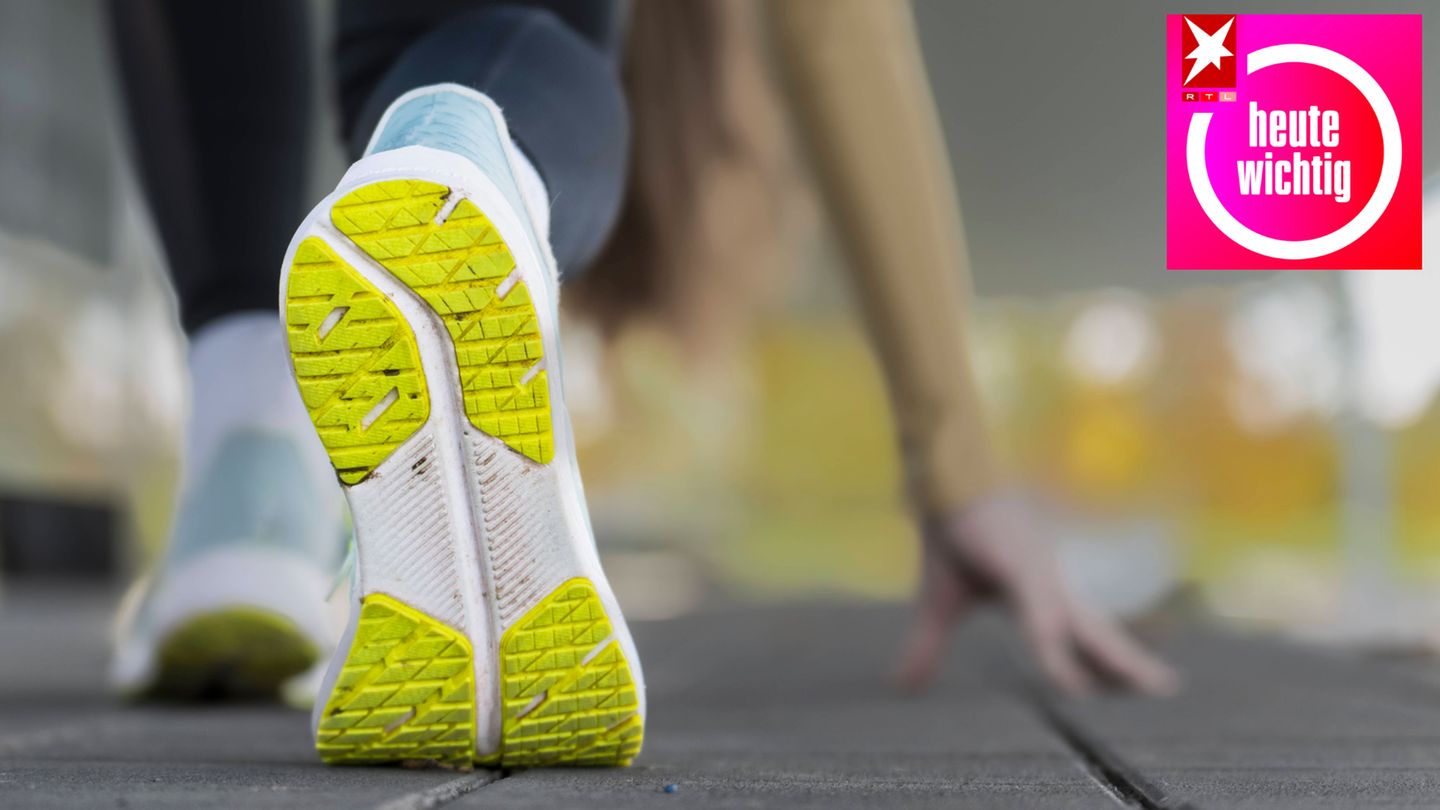 Sohle eines Sportschuhs einer jungen Frau, die sich vor dem morgendlichen Joggen im Freien dehnt