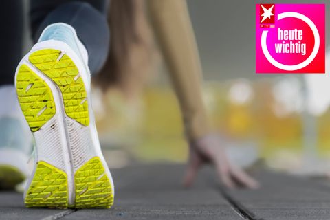 Sohle eines Sportschuhs einer jungen Frau, die sich vor dem morgendlichen Joggen im Freien dehnt