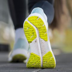 Sohle eines Sportschuhs einer jungen Frau, die sich vor dem morgendlichen Joggen im Freien dehnt