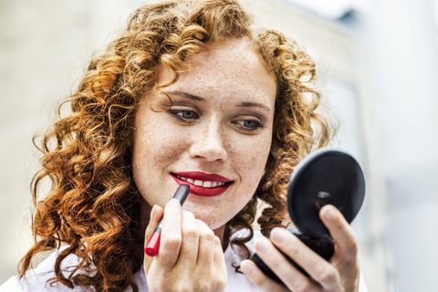 Frau trägt roten Lippenstift auf