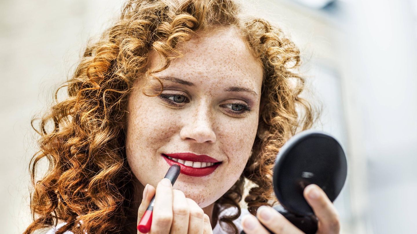 Frau trägt roten Lippenstift auf