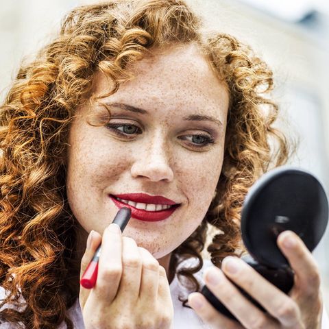 Frau trägt roten Lippenstift auf