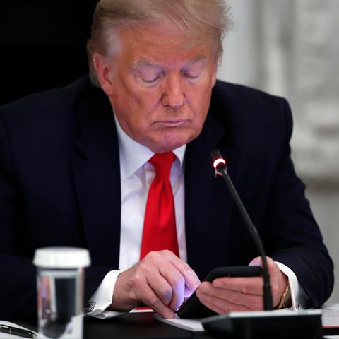 Donald Trump, ein älterer weißer Mann im Anzug, tippt auf seinem Smartphone herum