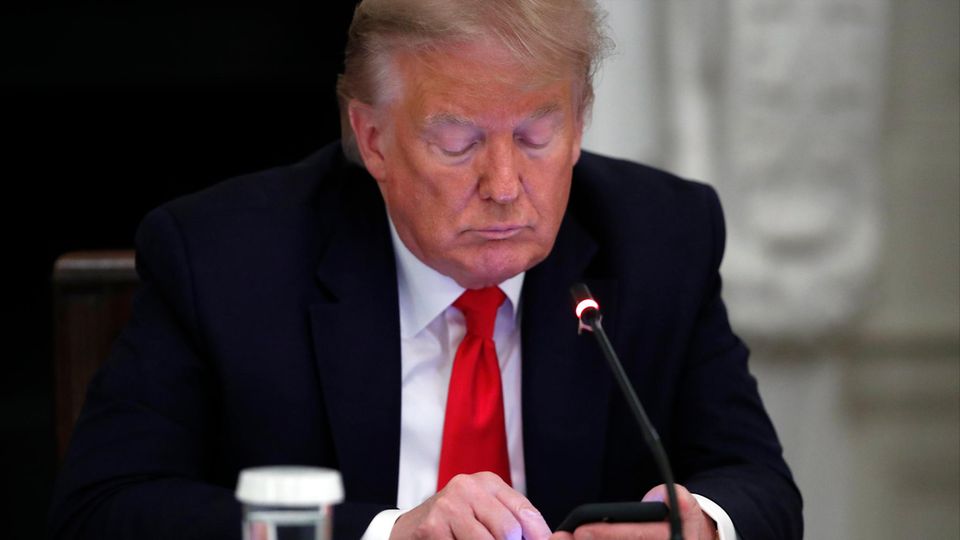 Donald Trump, ein älterer weißer Mann im Anzug, tippt auf seinem Smartphone herum