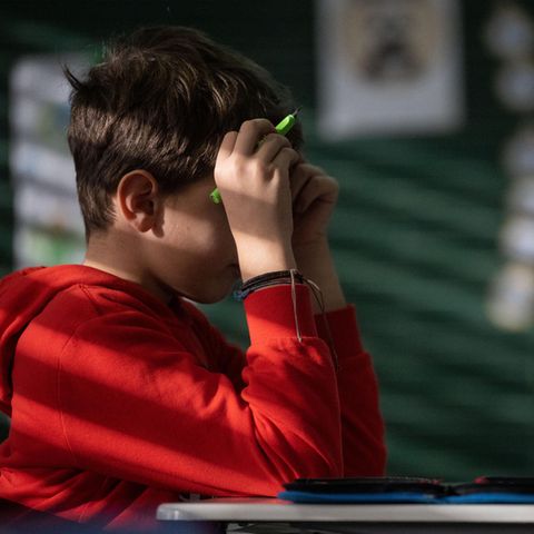 Ein Schüler hält beide Hände an den Kopf