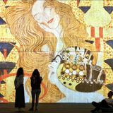 Eintauchen in eine andere Welt: Das ist das Konzept immersiver Ausstellungen, die aktuell  in vielen deutschen Städten zu sehen sind. Der Begriff steht für ein stark wachsendes Genre, das die Betrachter nicht wie üblich auf Abstand hält, sondern sie in das Werk miteinbezieht. Ausstellungen wie "Klimts Kuss", die aktuell in Berlin läuft, locken sie nicht nur Instagram-affine Besucher an, sondern auch diejenigen, die selten in Museen gehen. Die Veranstalter der Shows sehen sich dennoch nicht als Konkurrenz zu klassischen Kunsthäusern, sondern eher als Ergänzung. Vor allem in Zeiten, in denen sich mehrere Museen dem gleichen Künstler widmen, bieten sie eine Möglichkeit, besondere Bilder für alle verfügbar zu machen – wenn auch nur digital.