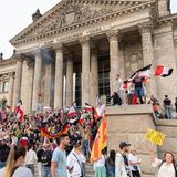 Teilnehmer einer Kundgebung gegen die Corona-Maßnahmen stehen auf den Stufen zum Reichstagsgebäude