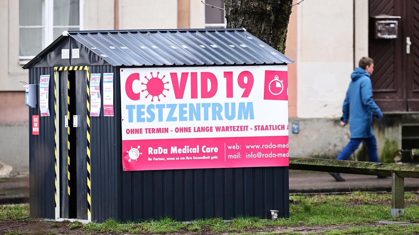 Corona: Ein Mann geht in Potsdam hinter einer in einer kleinen Hütte untergebrachten Covid-19-Teststation vorbei.