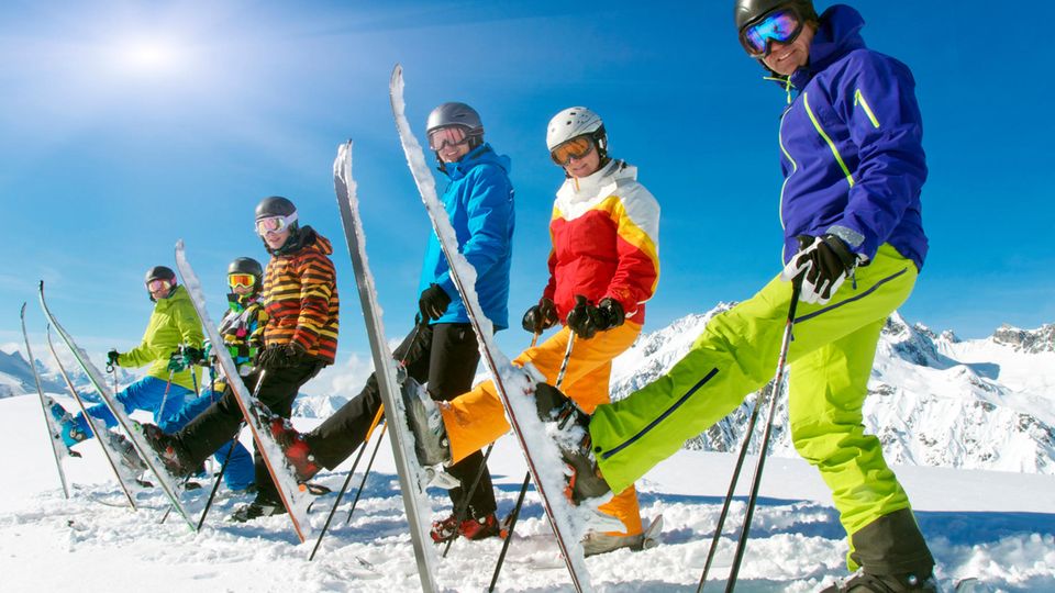 Eine Skigruppe in voller Montur und auf Skiern hat sich in einer Reihe aufgestellt.
