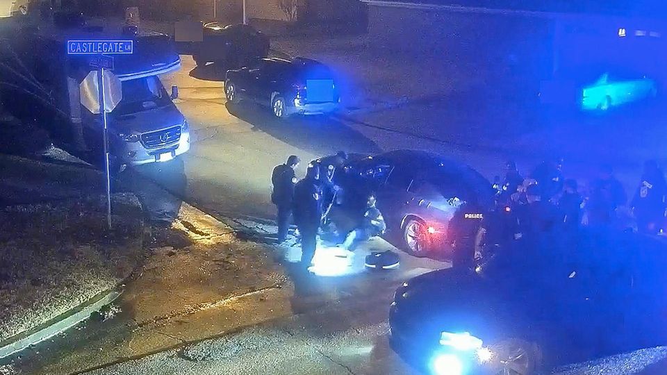 An ein Auto gelehnt sitzt Tyre Nichols umringt von Polizisten auf einer Straße in Memphis.