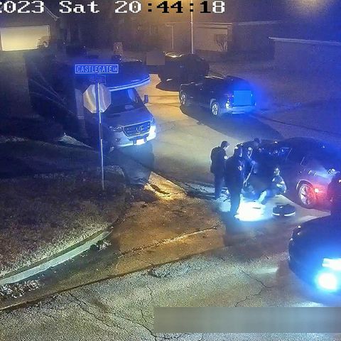 An ein Auto gelehnt sitzt Tyre Nichols umringt von Polizisten auf einer Straße in Memphis.